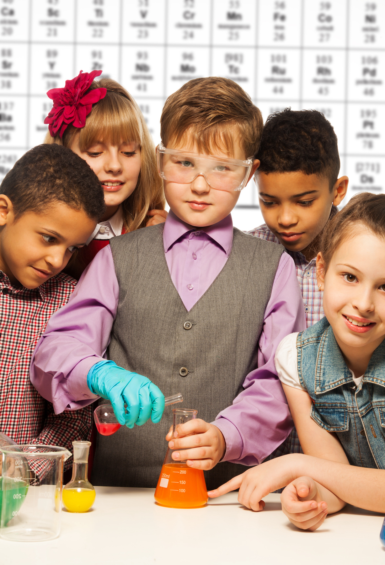 Group of diversity kids boys and girls conductive experiments with periodic table on background