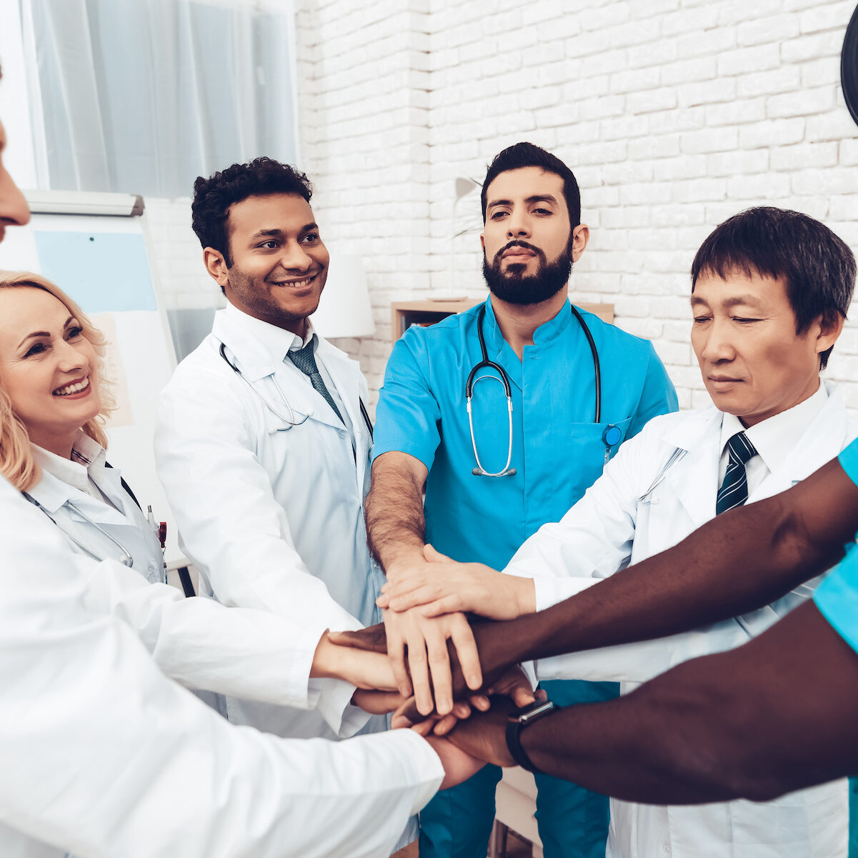 Professional Doctors Holding Each Other Hands. Multinational Medician Meeting. Teamwork Connection. Clinician Team Group. Working Together. Office Friendship. Partnership Arms Shaking.